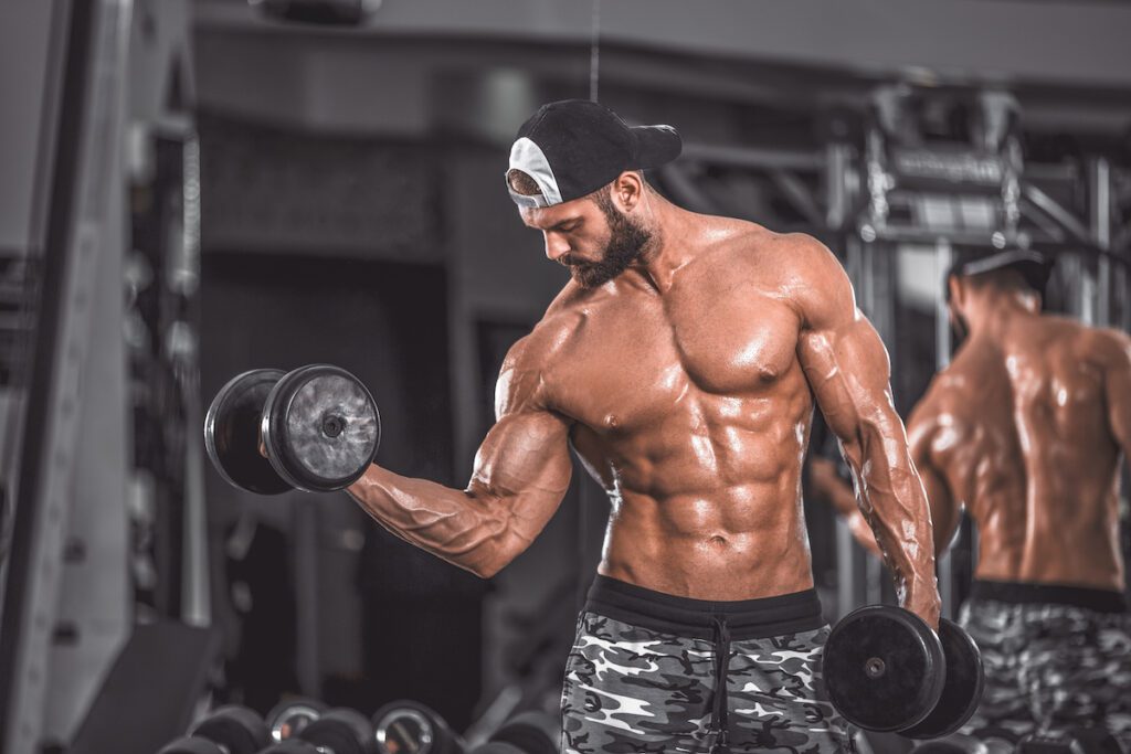 man bodybuilder dumbbell curl biceps chest six pack gym