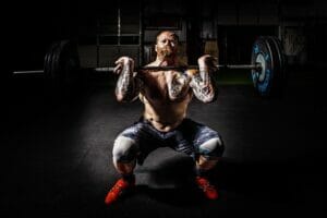 tips to help you reach your fitness goals. Man performs a front squat.