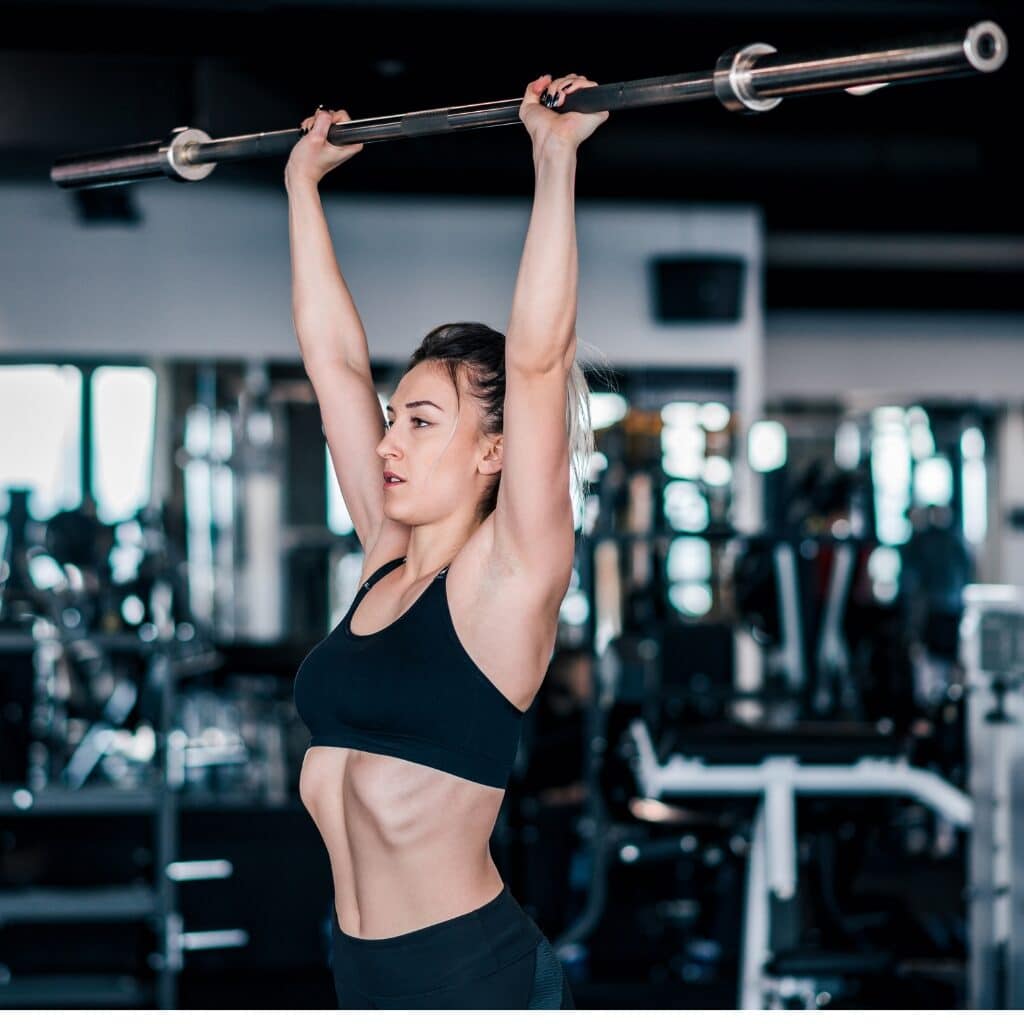 5 Ways You Can Improve Your Shoulder Workouts for Greater Gains  Woman Performing Barbell Shoulder Press