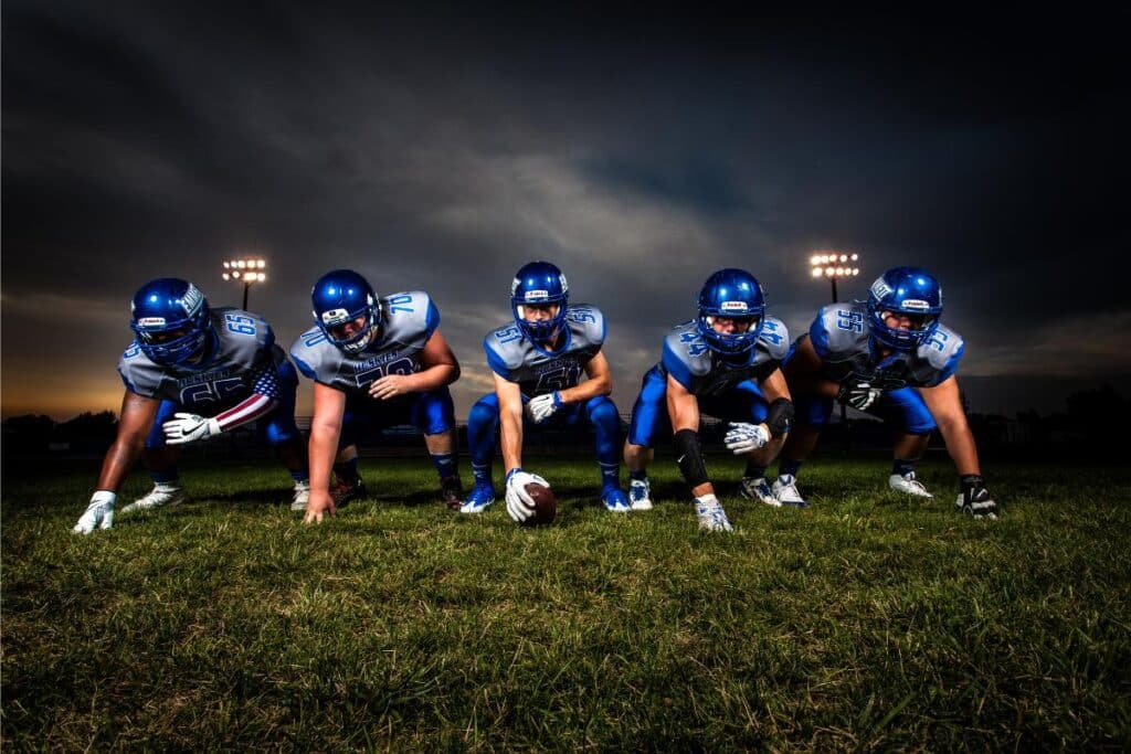 Football Players in Blue Jersey Lined Under Grey White Cloudy Sky during Sunset(opens in a new tab or window)