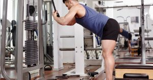 A fit man with good form uses a double-end rope grip to perform an exercise on a weighted cable machine.