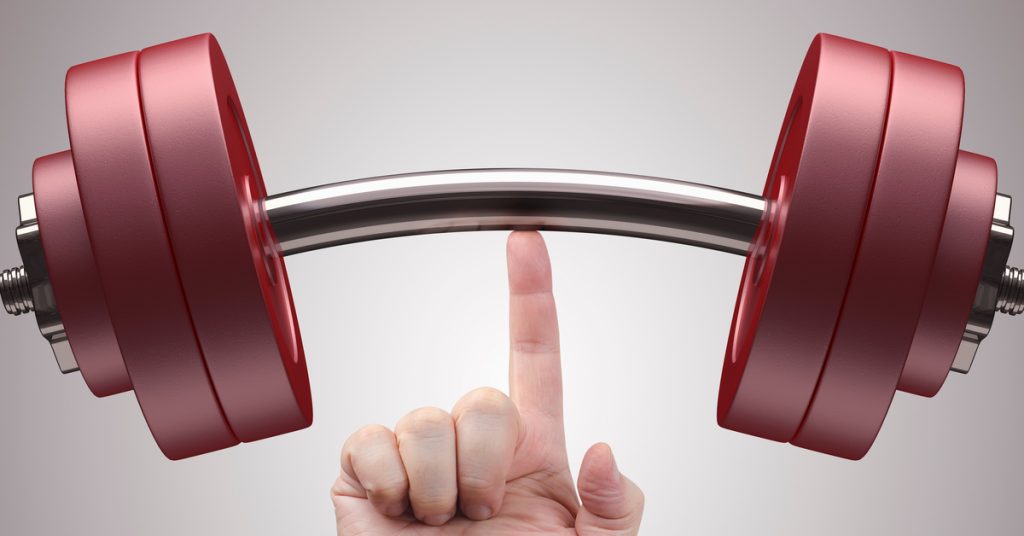 A person balancing a small dumbbell with thick red weight plates on their index finger as it is pointed up.